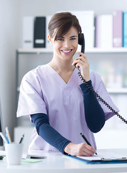 Young practitioner doctor working at the clinic reception desk, she is answering phone calls and scheduling appointments