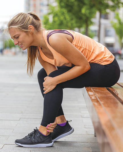 Running injury leg accident- sport woman runner hurting holding painful sprained ankle in pain. Athlete woman has ankle injury, sprained ankle during running training. Space for text