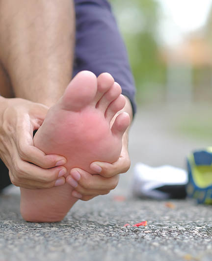 Young fitness man holding his sports leg injury, muscle painful during training. Asian runner having foot ache and problem after running and exercise outside in summer