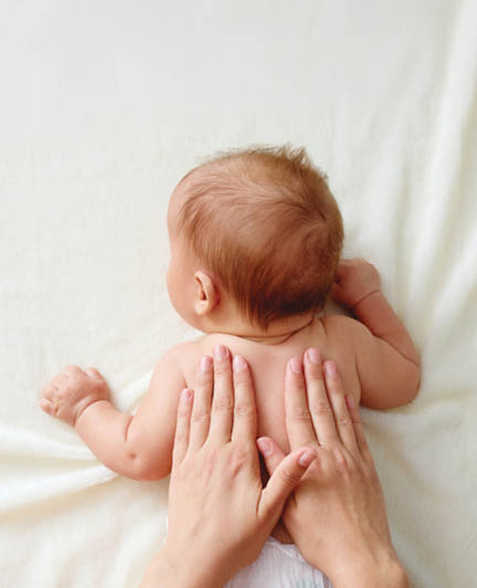 Chiropractic manual therapist manipulating child's back baby girl receiving massage therapy ensuring his delicate muscles receive proper care and relaxing treatment at home
